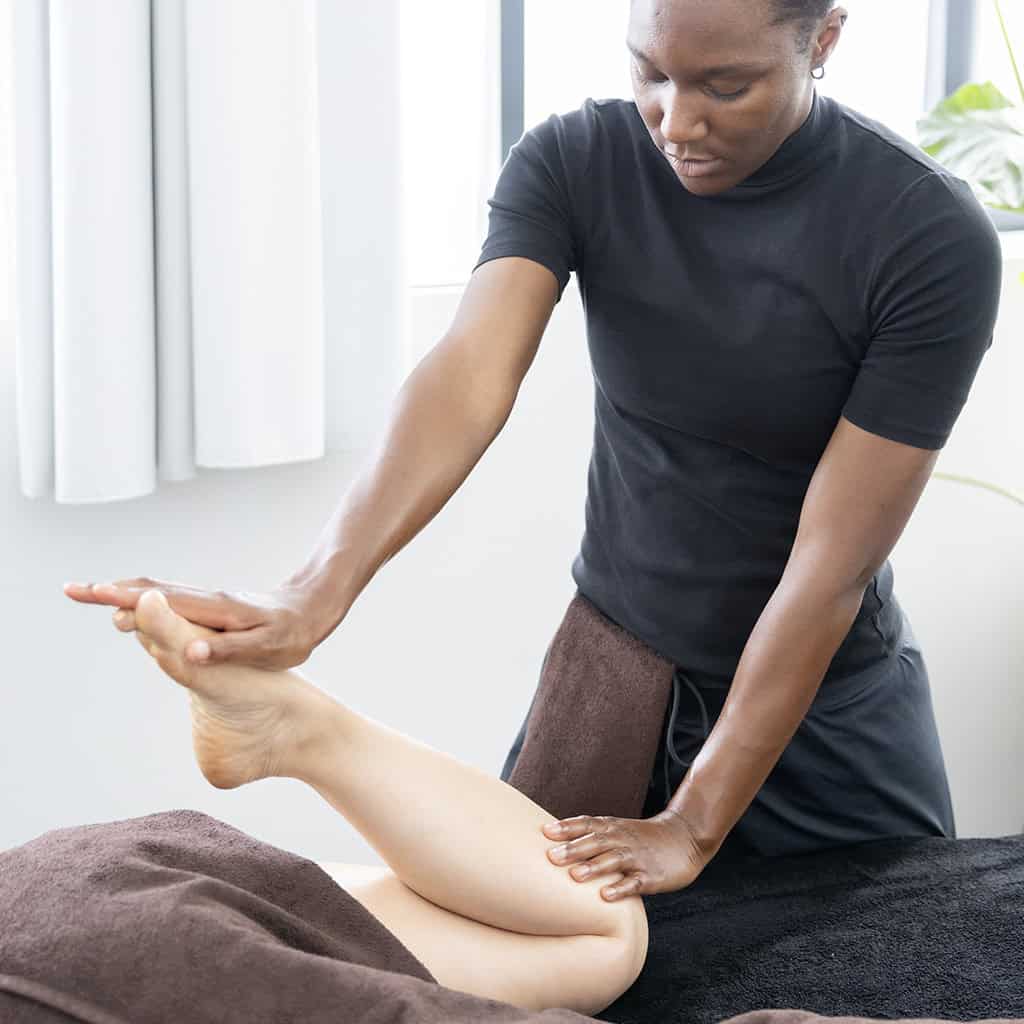 Ambre de vie faisant un massage thaÏ à l'huile sur la jambe de sa cliente